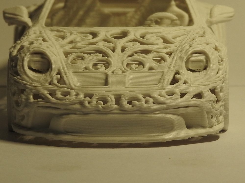 Close up of the ivory lattice on the front of the printed GT3, curling cells framing both headlights, with fine layer lines visible across every surface